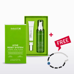 Innate Essentials Acne Reset System gift set featuring a green outer box, a green inner tray with a white tube and green pump bottle, plus a red 'FREE' badge and a black beaded evil eye bracelet on a white background.