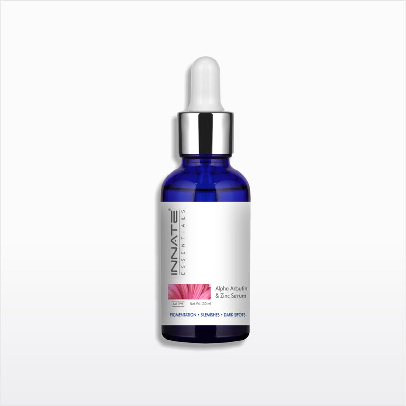 A cobalt blue glass dropper bottle of Innate Cosmetics Alpha Arfudin & Linc Serum, featuring a white label with a pink flower graphic and a silver collar with a white dropper cap, set against a light gray background.