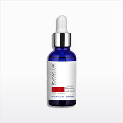 A single dropper bottle of Innate Cosmetics Hyaluronic Acid Serum on a light gray gradient background. The bottle is cobalt blue glass with a white label, a silver collar, and a white rubber dropper cap.