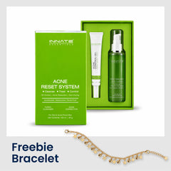 Innate Essentials Acne Reset System gift set with a bright green box, green treatment tube, and green pump bottle, displayed alongside a gold floral chain bracelet on a white background with a gray footer containing the text 'Freebie Bracelet'.